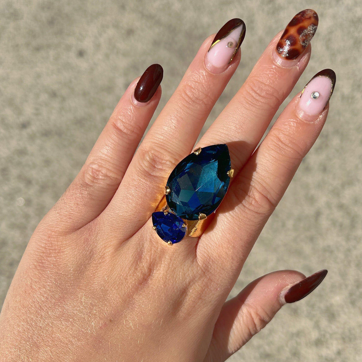 Bague Calypso Azur Crézus avec grand cristal bleu nuit en forme de goutte, petit cristal bleu saphir et monture dorée martelée – Divinity Sète.