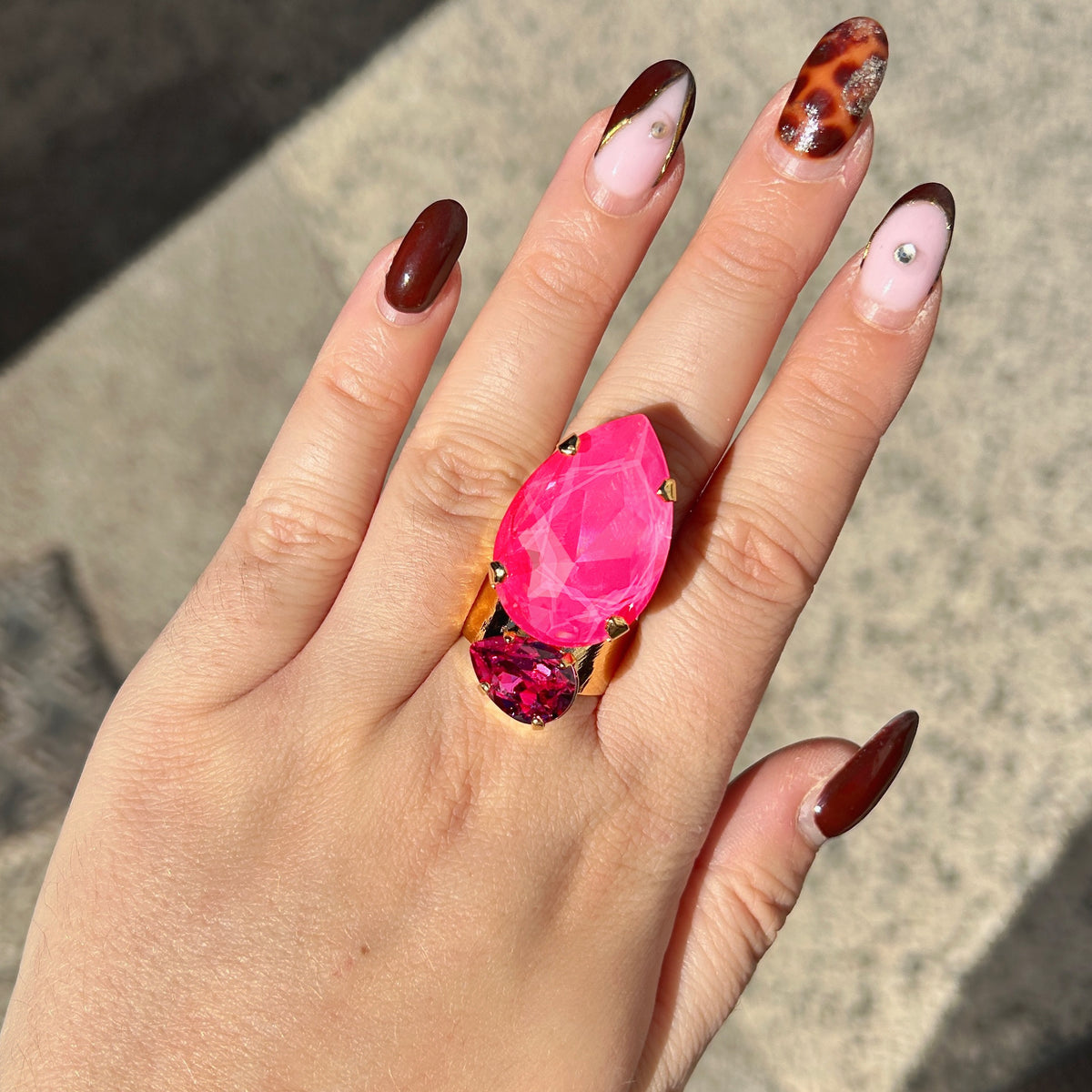 Bague Calypso Orchidée Crézus avec grand cristal rose orchidée en forme de goutte, petit cristal rose fuchsia facetté, sertissage à griffes dorées et anneau large martelé.