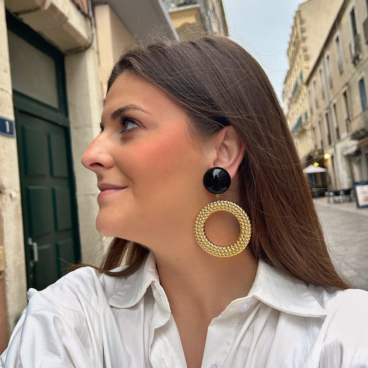 Boucles d’oreilles Avena Gold à clips Francine Bramli Paris, cabochons ronds noirs brillants et grands anneaux circulaires dorés ornés de petites perles en relief.