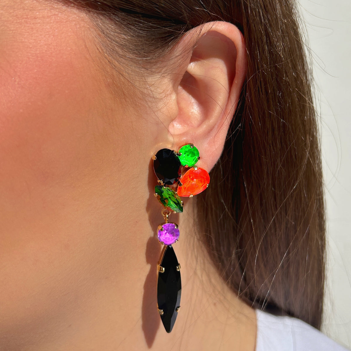 Boucles d’oreilles pendantes à clips Kalyx Fluo Crézus avec cristaux vert fluo, orange, violet et noir, longues navettes noires et montures dorées – Divinity Sète