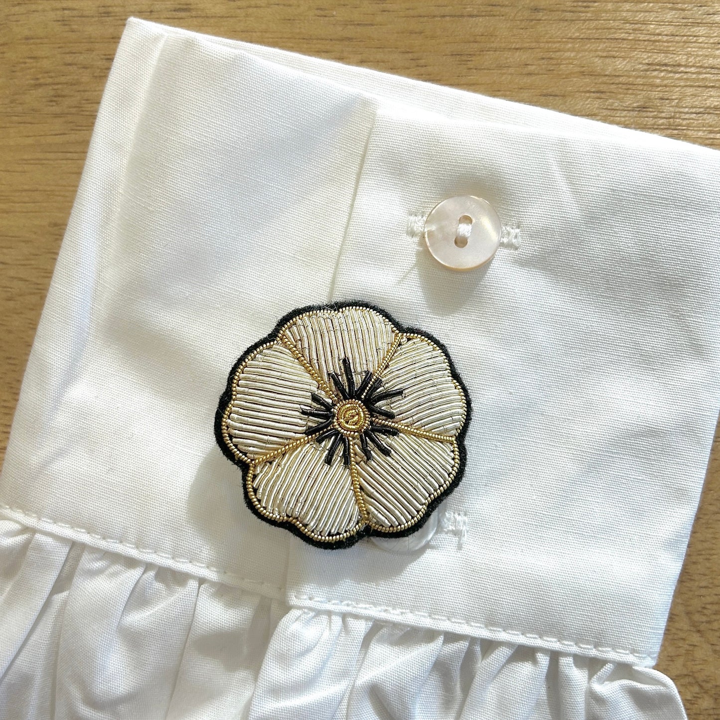 Détail broche camélia brodé fils dorés