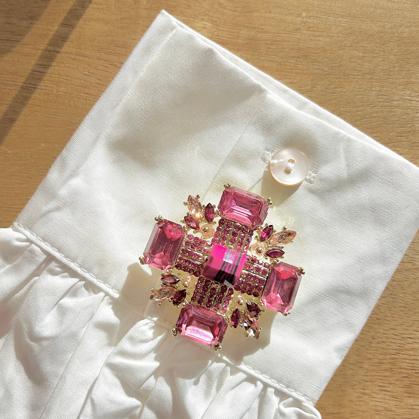 Détail broche croix rose monture dorée