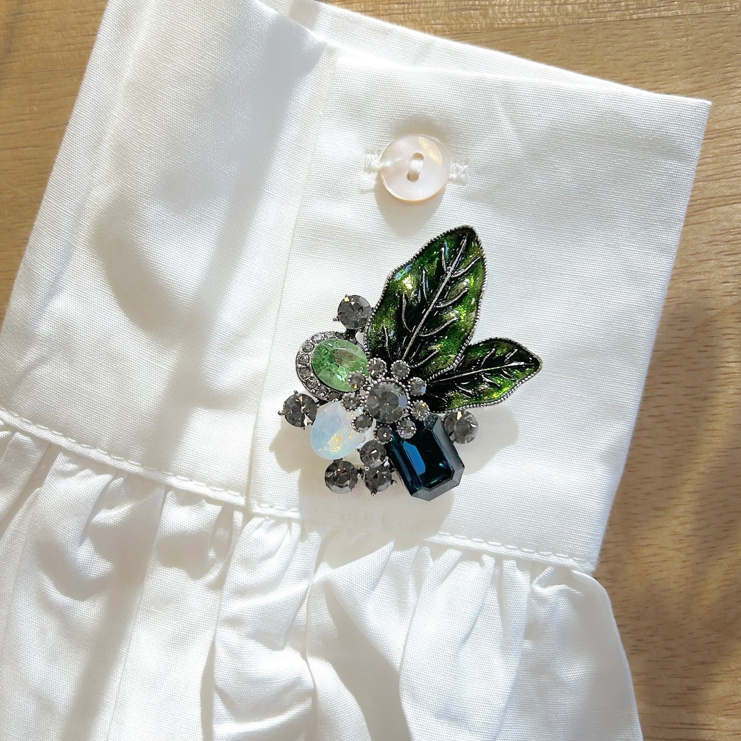 Détail broche feuillage vert pierres facettées