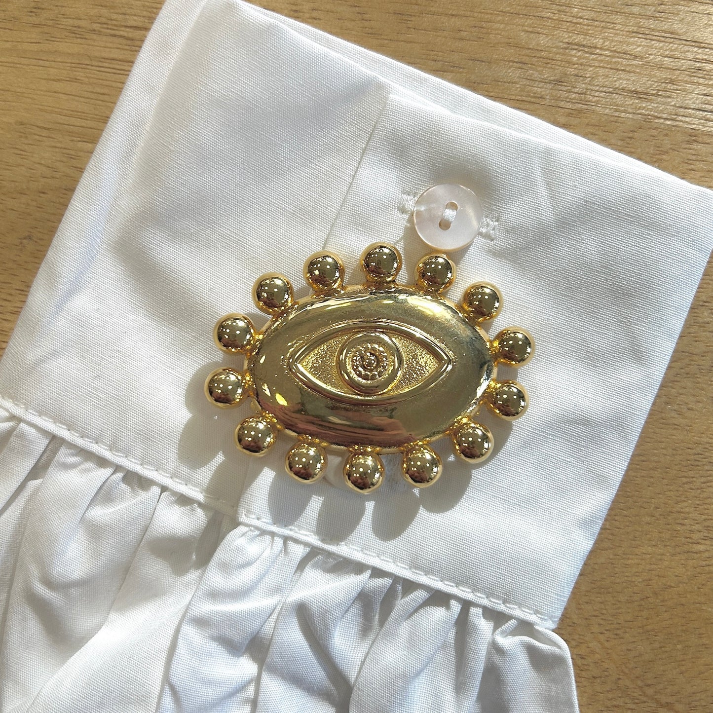 Détail broche œil doré finition brillante