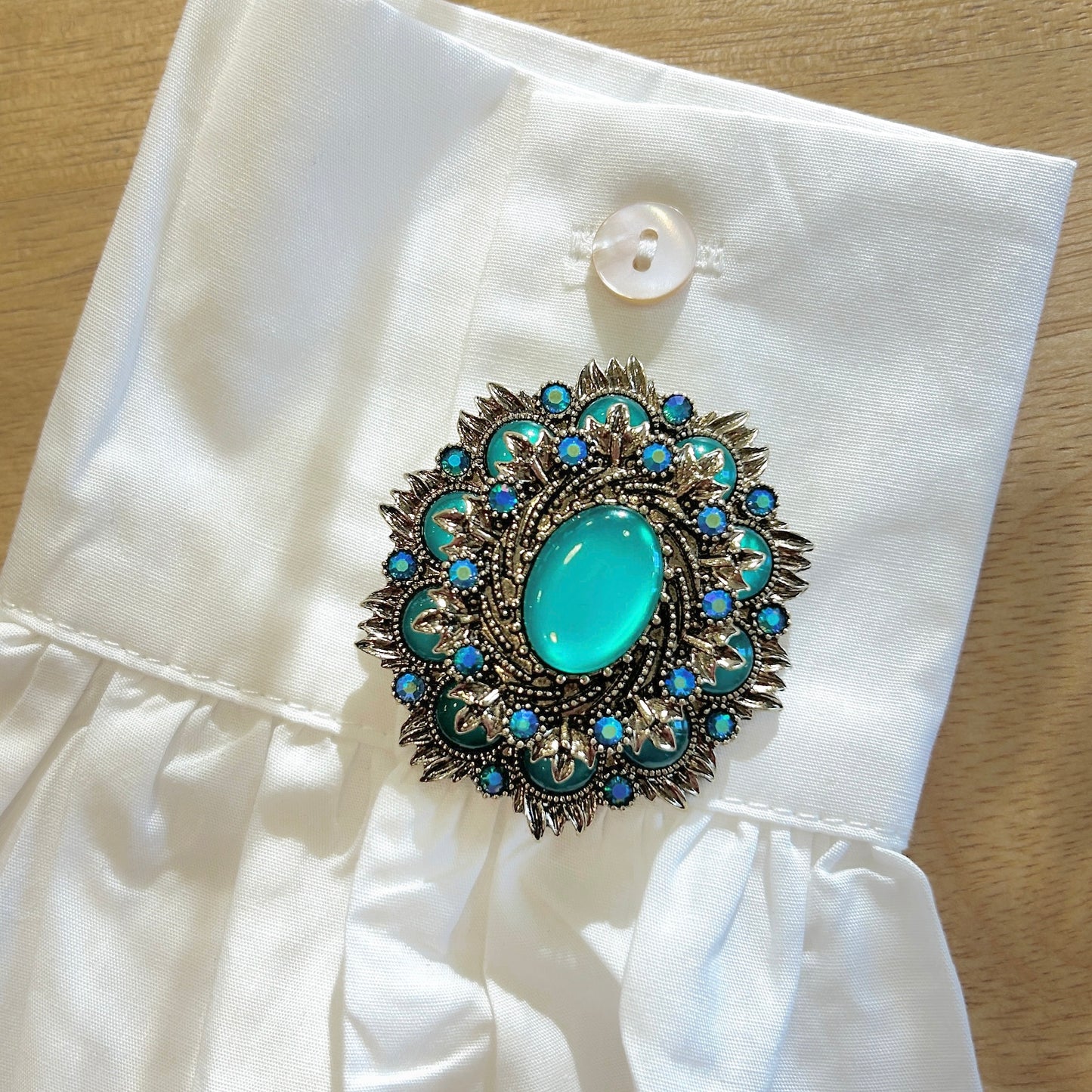 Détail broche rosace bleu turquoise strass