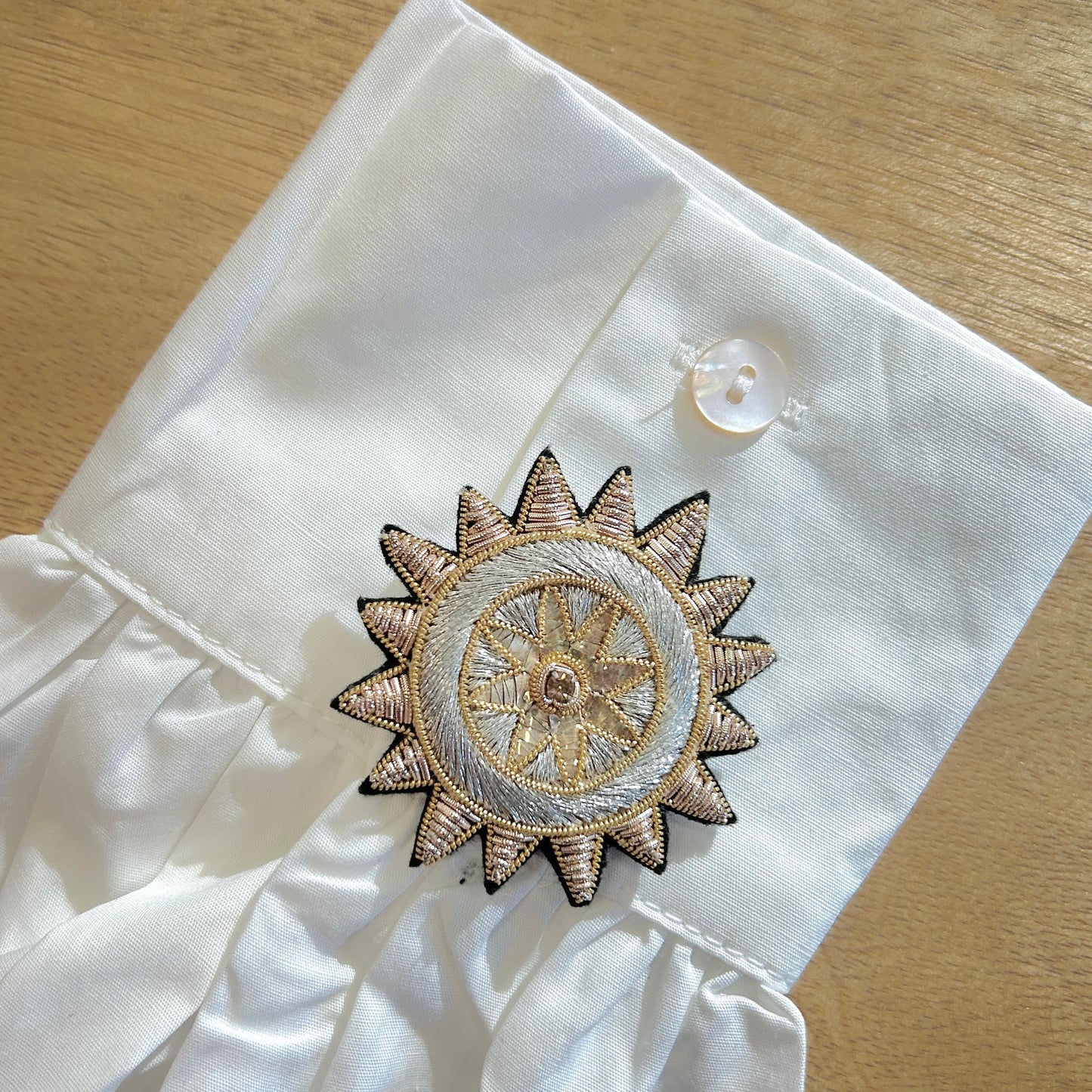Détail broche soleil brodée dorée et argentée