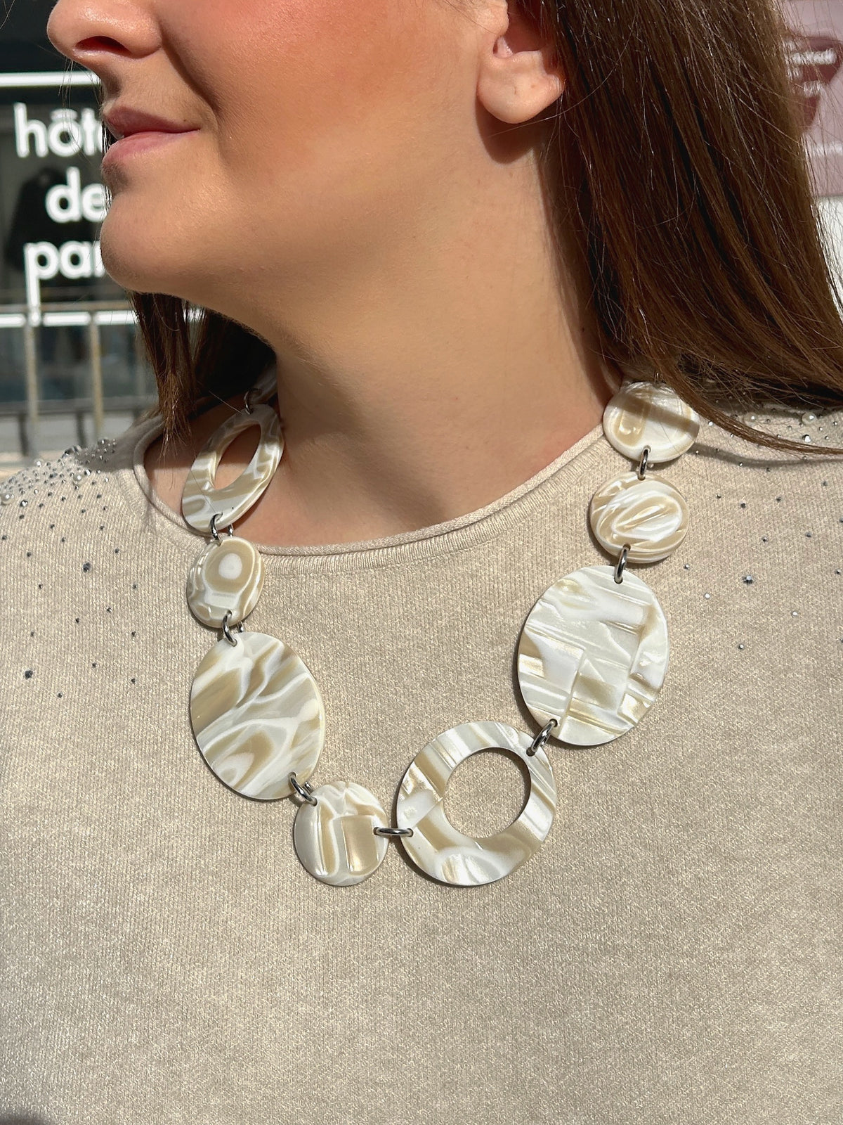 Collier Alba Francine Bramli Paris composé de médaillons ronds marbrés blanc nacré et beige, alternant formes pleines et anneaux ajourés.