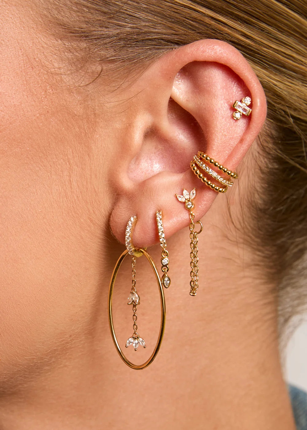 Earcuff Shiny Camden Gold MYA BAY à trois anneaux dorés, deux rangées de perles dorées et une rangée centrale de cristaux blancs, chez Divinity Sète.