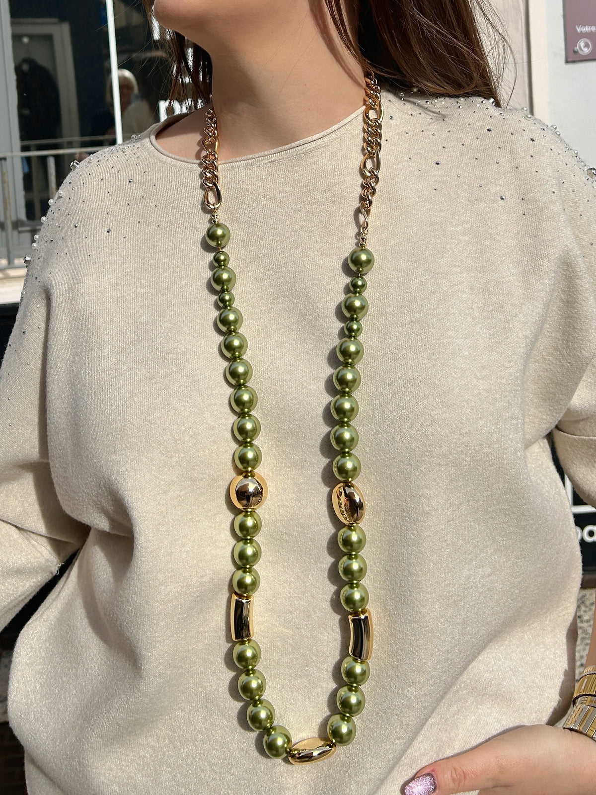 Sautoir Mariella Kaki Francine Bramli Paris, long collier composé de perles vert kaki nacrées, de maillons de chaîne et d'éléments dorés.