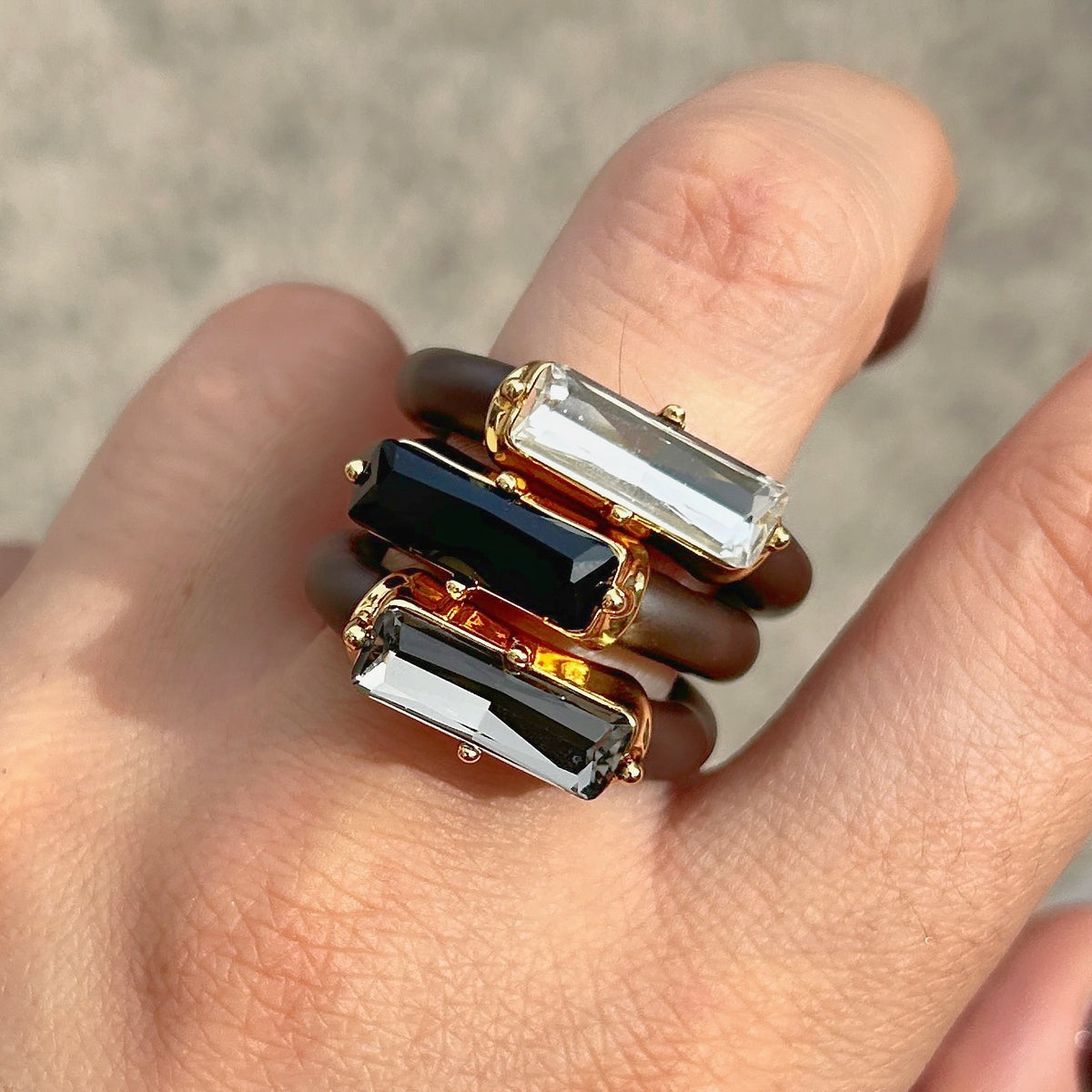 : Bague Riva Gris avec cristal rectangulaire facetté gris fumé, monture dorée et anneau marron