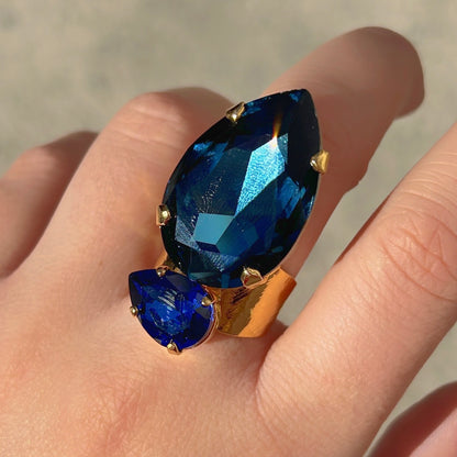 Bague Calypso Azur Crézus avec grand cristal bleu nuit en forme de goutte, petit cristal bleu saphir et monture dorée martelée – Divinity Sète.