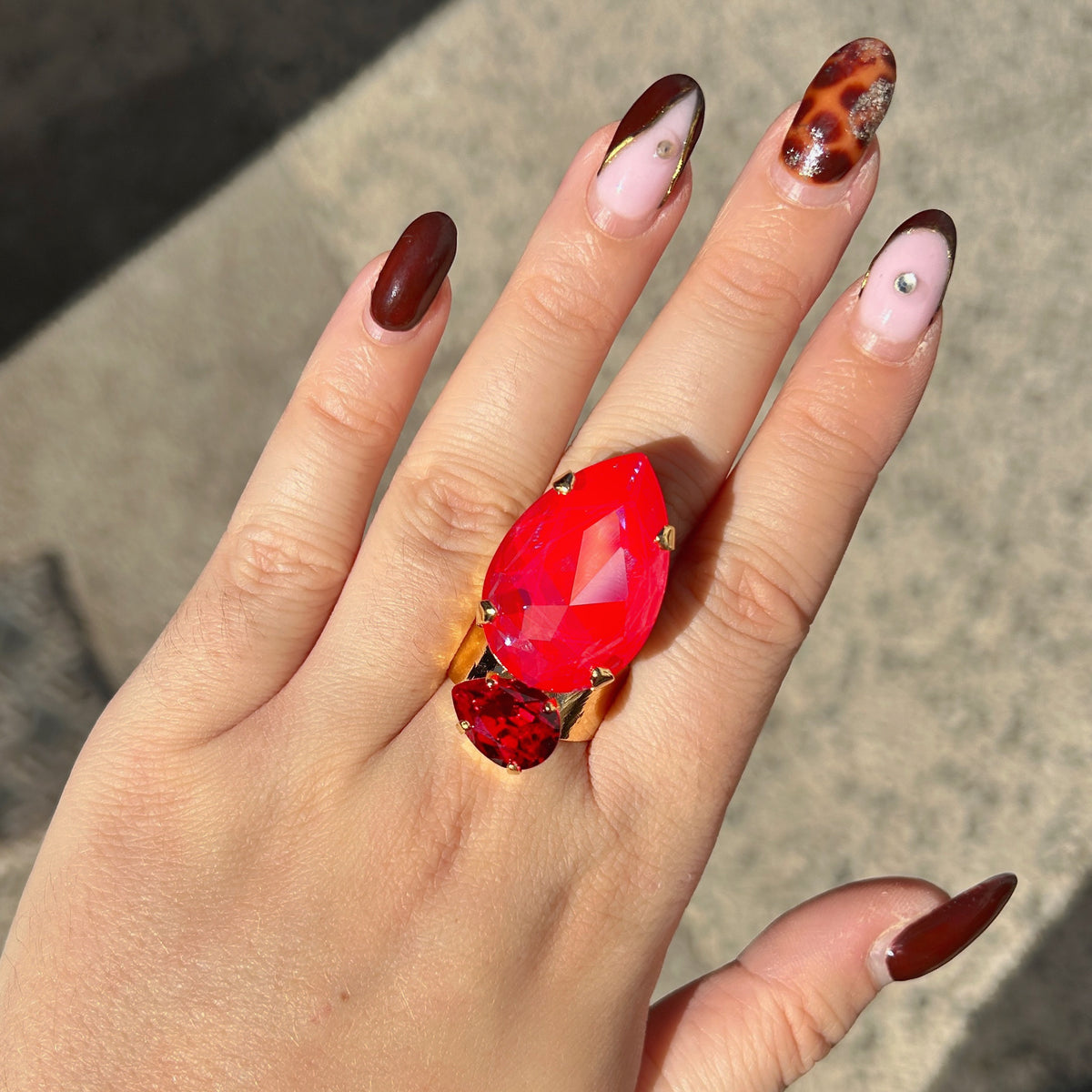 Bague Calypso Cerise Crézus avec grand cristal rouge cerise en forme de goutte, petit cristal rouge rubis et large monture dorée martelée – Divinity Sète.
