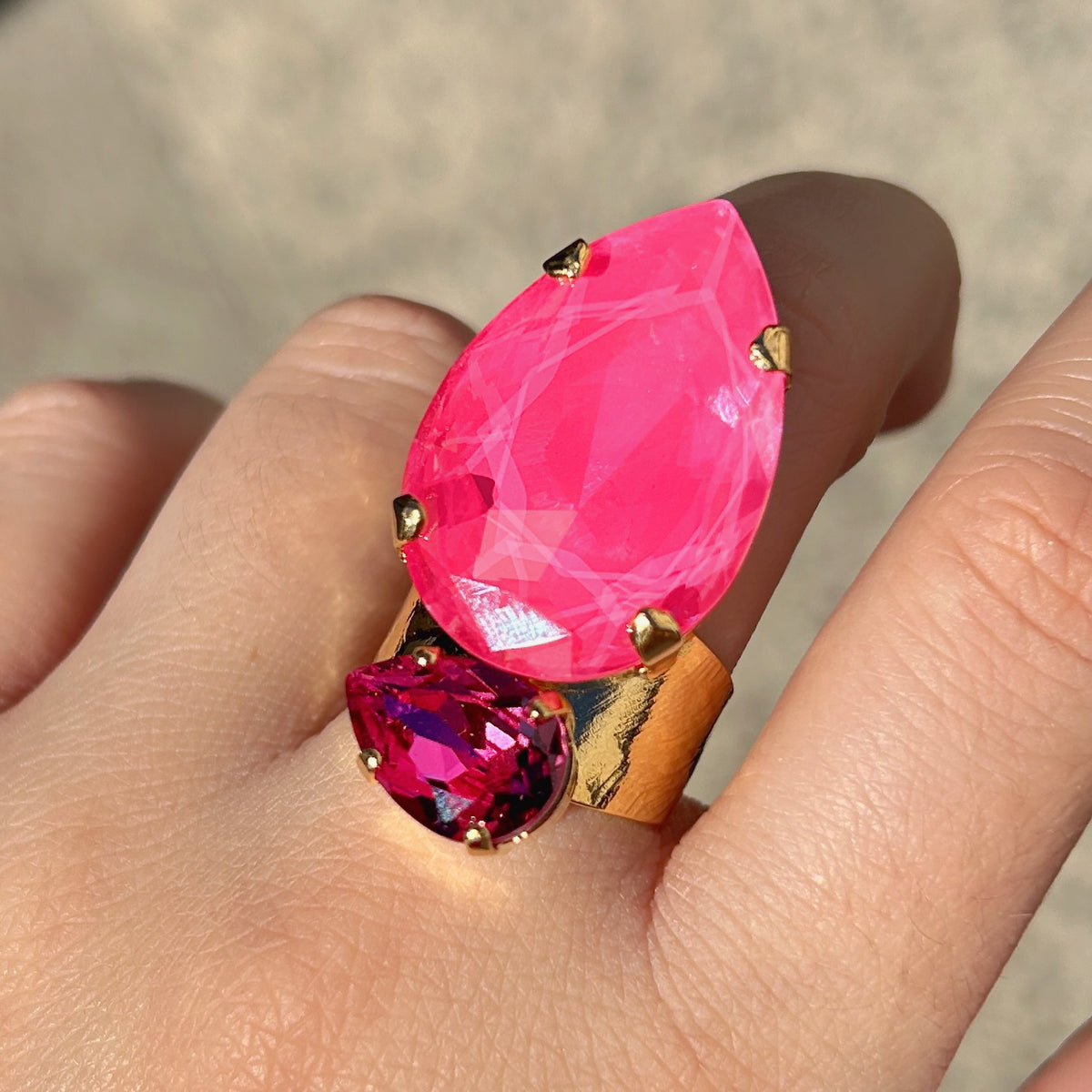 Bague Calypso Orchidée Crézus avec grand cristal rose orchidée en forme de goutte, petit cristal rose fuchsia facetté, sertissage à griffes dorées et anneau large martelé.