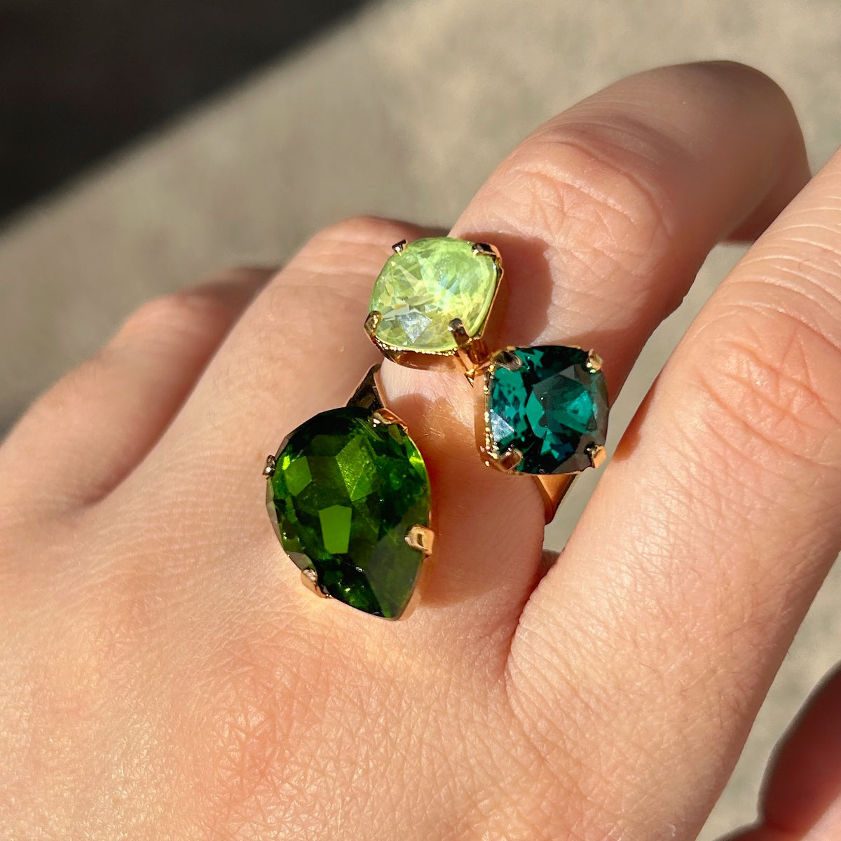 Bague Dalia Émeraude Crézus ornée de trois cristaux facettés vert émeraude, vert anis et vert olive, sertis sur une monture dorée asymétrique – Divinity Sète.