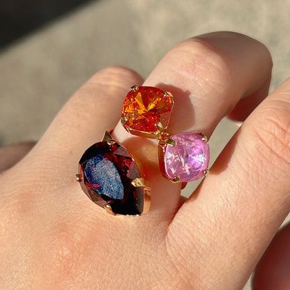 Bague Dalia Figue Crézus avec trois cristaux facettés couleur figue, orange et rose lilas, sertis sur une monture dorée asymétrique – Divinity Sète.