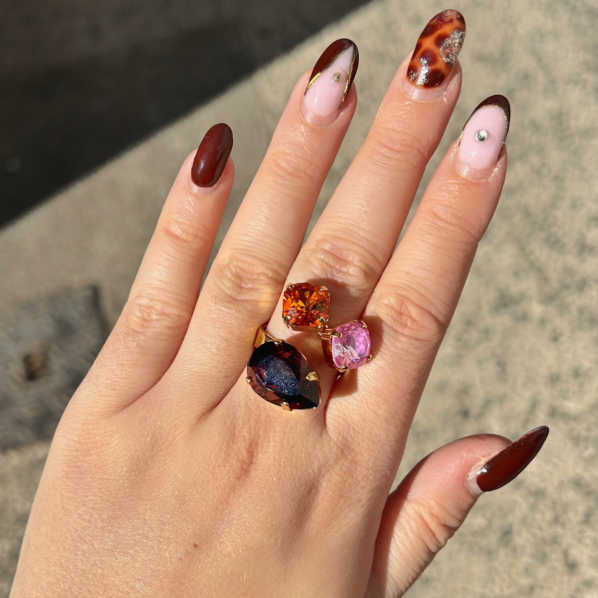 Bague Dalia Figue Crézus avec trois cristaux facettés couleur figue, orange et rose lilas, sertis sur une monture dorée asymétrique – Divinity Sète.