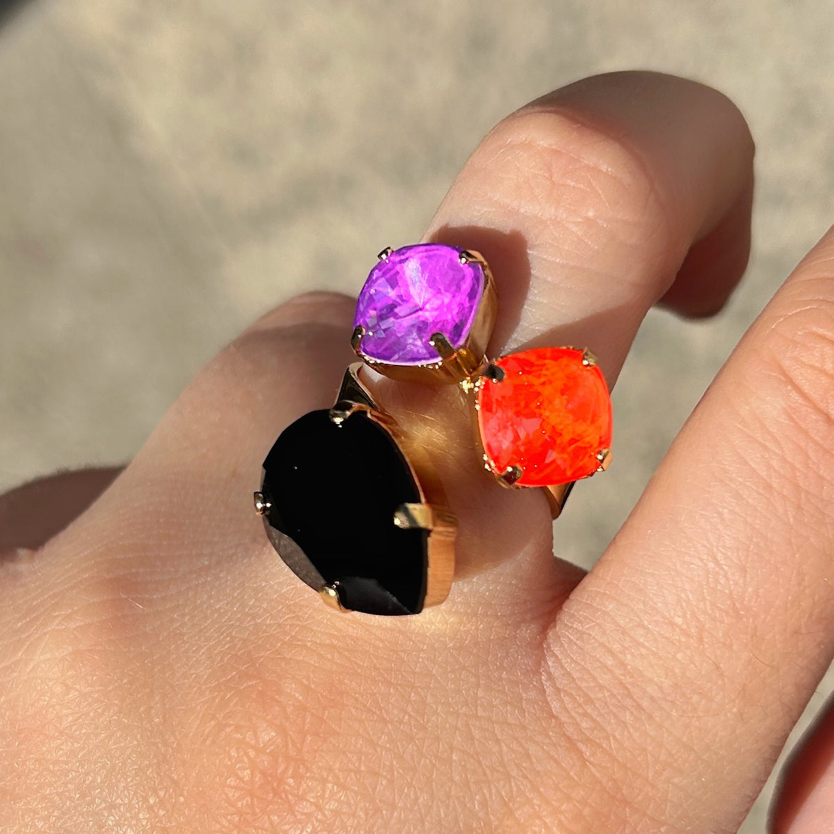 Bague Dalia Fluo Crézus avec trois cristaux facettés violet, orange fluo et noir, sertis sur une monture dorée asymétrique – Divinity Sète.