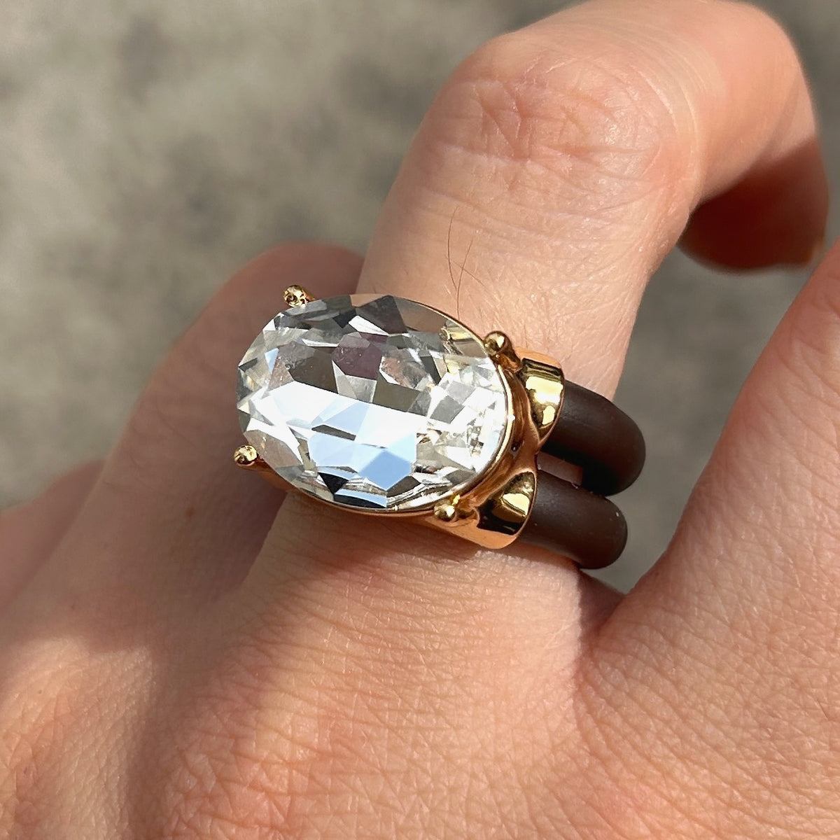 Bague Diva Blanc avec grand cristal ovale facetté transparent, monture dorée et double anneau marron