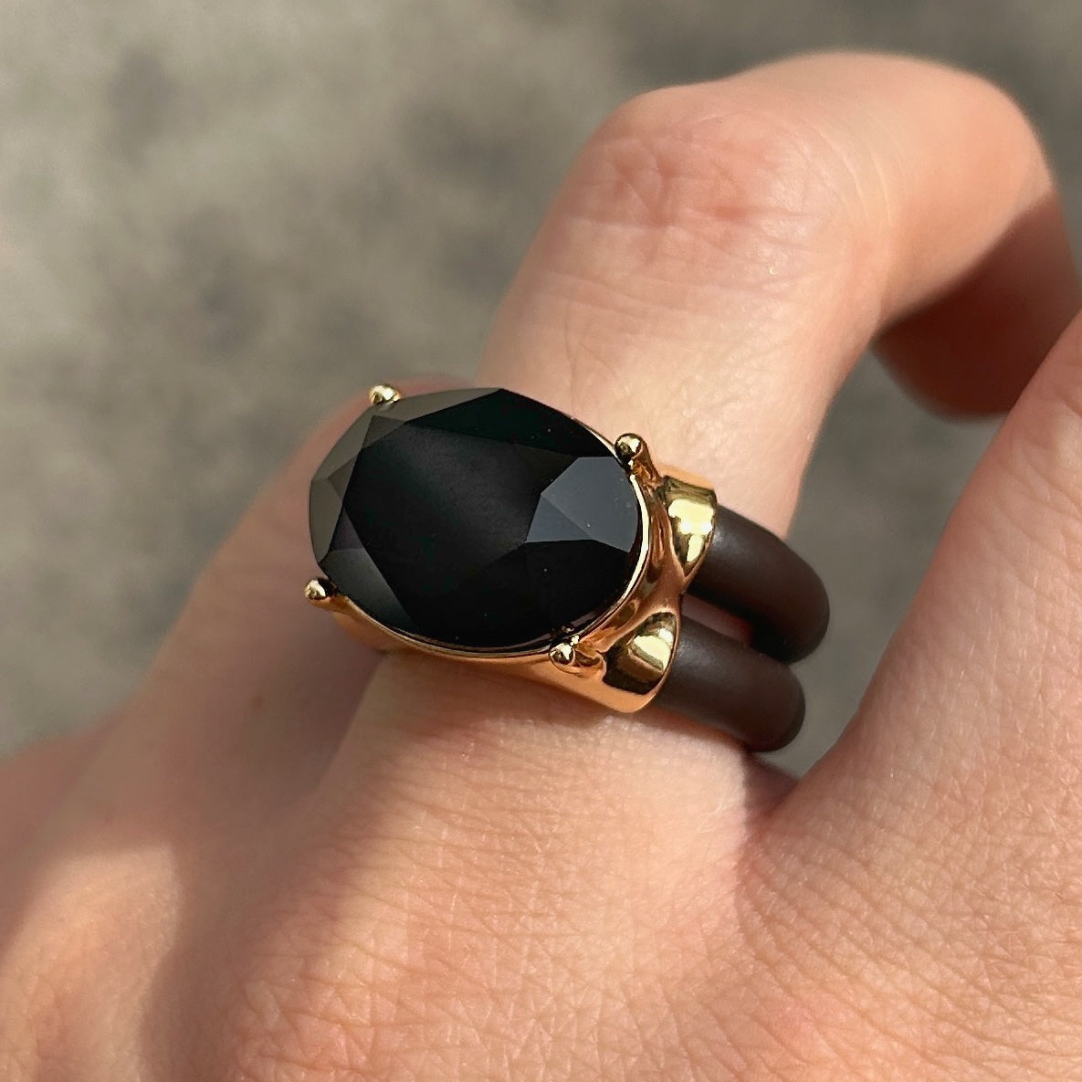 Bague Diva Noir avec grand cristal ovale noir facetté, monture dorée et double anneau marron