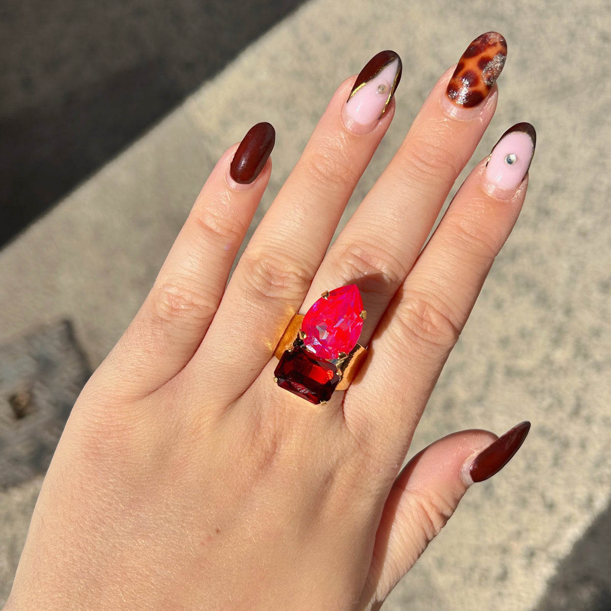 Bague Lyra Cerise Crézus avec cristal rose cerise en forme de goutte et cristal rectangulaire rouge rubis, sertis sur une large monture dorée texturée – Divinity Sète.