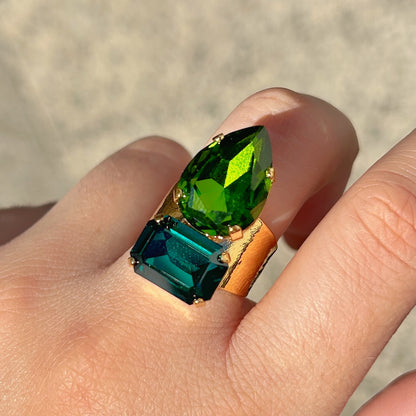 Bague Lyra Émeraude Crézus avec deux cristaux facettés vert émeraude et vert profond, en forme de goutte et de rectangle, sur une large monture dorée texturée – Divinity Sète.
