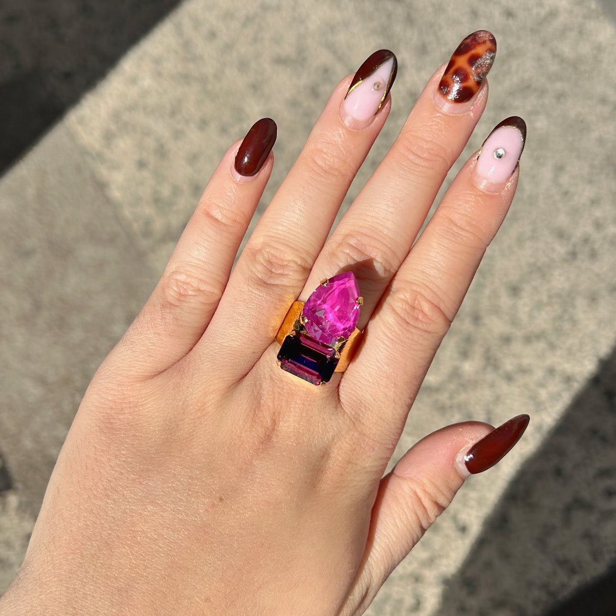 Bague Lyra Mûre Crézus avec cristal rose orchidée en forme de goutte et cristal rectangulaire violet mûre, sertis sur une large monture dorée texturée – Divinity Sète.