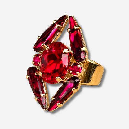 Bague Mira Cerise Crézus avec grand cristal ovale rouge cerise, quatre cristaux allongés rouge grenat, deux petits cristaux ronds rose cerise et monture dorée à anneau large.