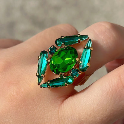 Bague Mira Émeraude Crézus avec grand cristal ovale vert émeraude, quatre cristaux allongés turquoise, petits cristaux vert canard et monture dorée à anneau large.