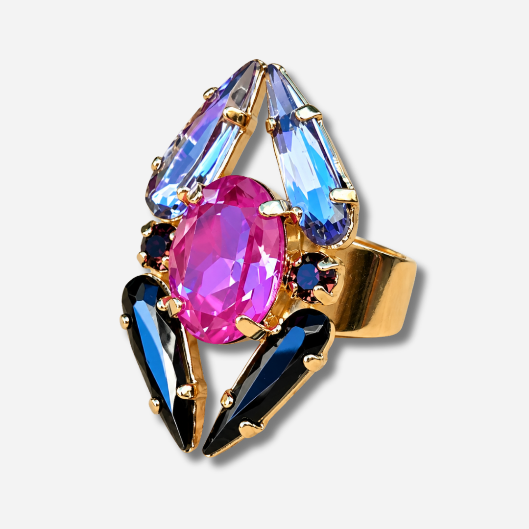 Bague Mira Mûre Crézus avec grand cristal ovale rose fuchsia, cristaux pointus noirs et bleu lavande, petits cristaux prune et monture dorée à anneau large