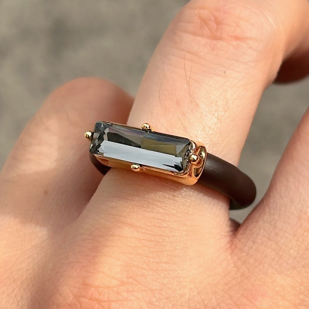 : Bague Riva Gris avec cristal rectangulaire facetté gris fumé, monture dorée et anneau marron