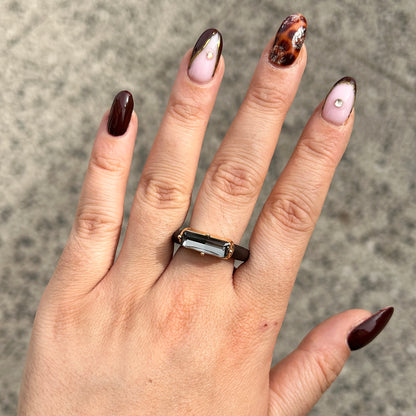 : Bague Riva Gris avec cristal rectangulaire facetté gris fumé, monture dorée et anneau marron