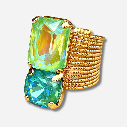 Bague Velora Lagoon Crézus dorée à large anneau composé de rangées perlées, ornée de deux grands cristaux facettés vert anis aux reflets jaunes et bleu lagon turquoise, sertis de griffes dorées.