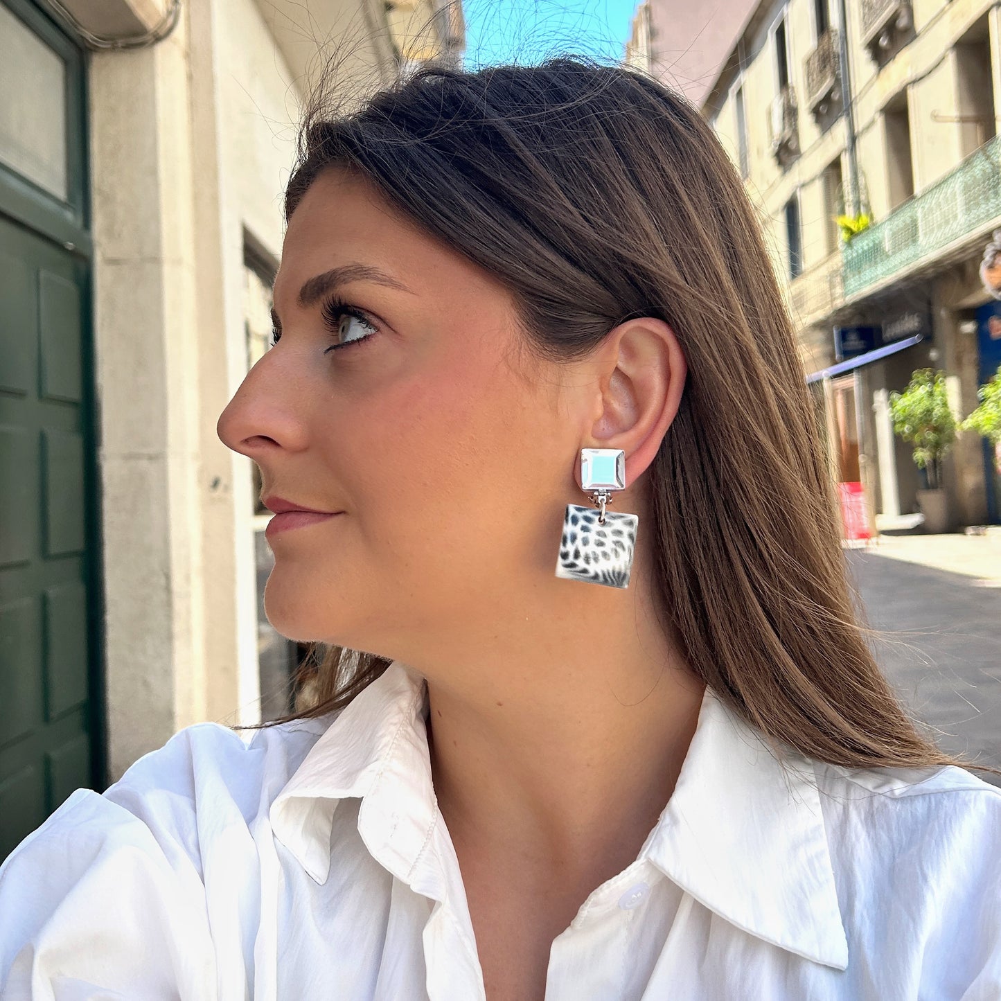 Boucles Albertine Blanc Francine Bramli Paris avec puce carrée argentée miroir et pendentif carré noir et blanc motif animalier, portées sur mannequin chez Divinity Sète.