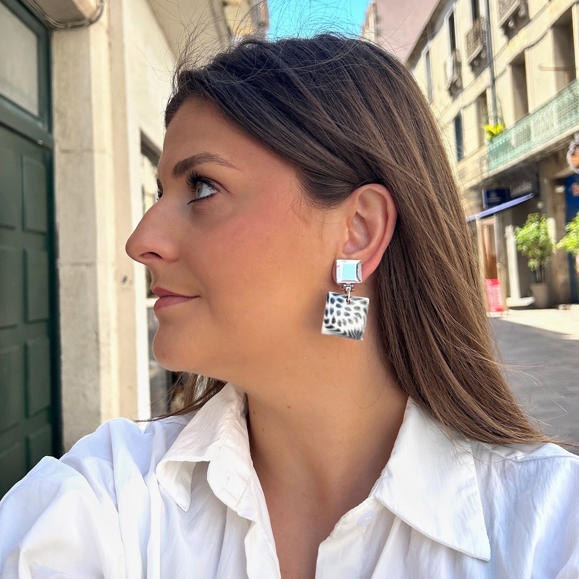 Boucles Albertine Blanc Francine Bramli Paris avec puce carrée argentée miroir et pendentif carré noir et blanc motif animalier, portées sur mannequin chez Divinity Sète.