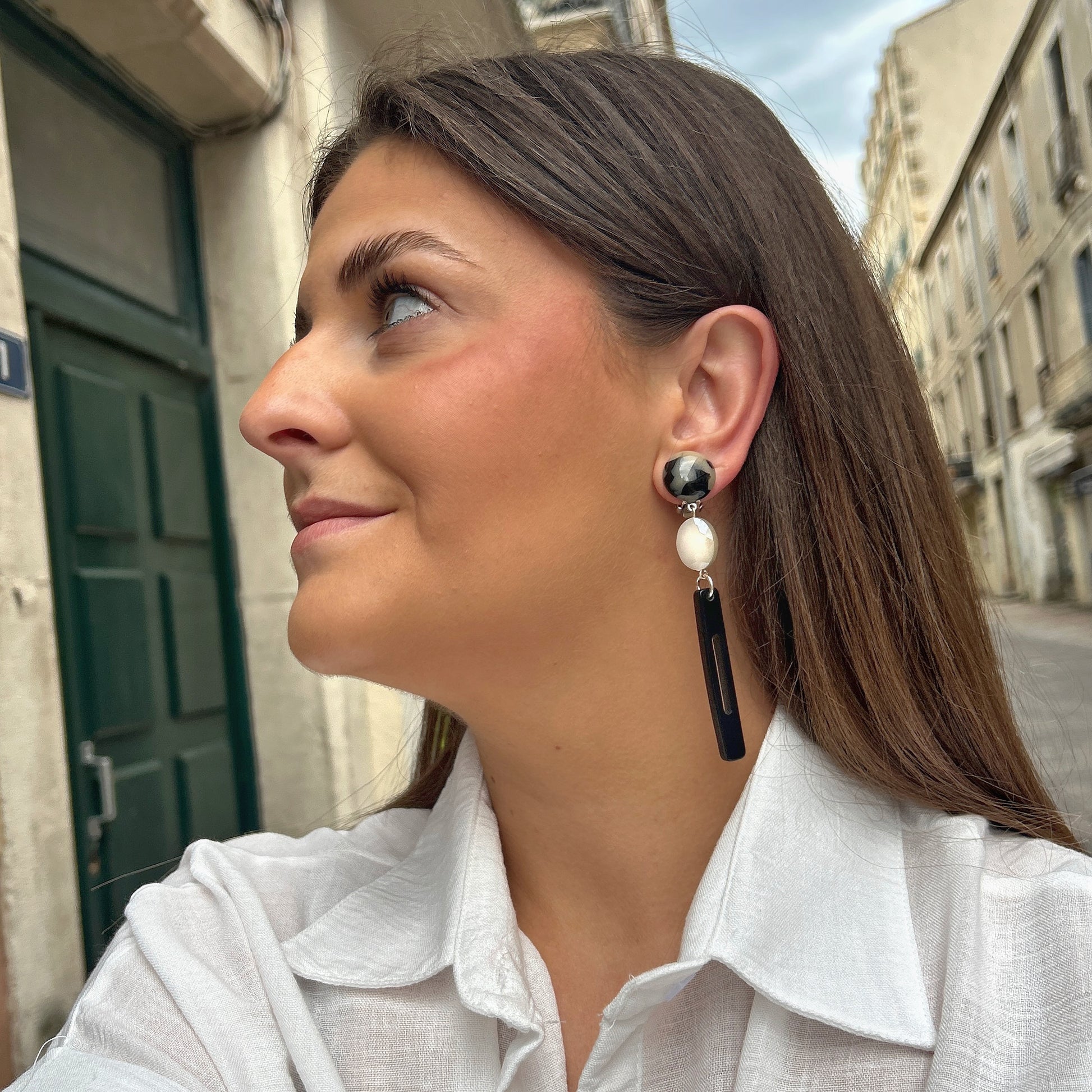 Boucles Bâton Écaille Noir et Blanc Francine Bramli Paris avec résine marbrée noire et ivoire, perle facettée blanche et pendentif graphique noir.