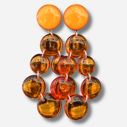 Boucles d'oreilles Cristallines Orange Francine Bramli Paris en résine orange translucide avec effet lumineux et design graphique.