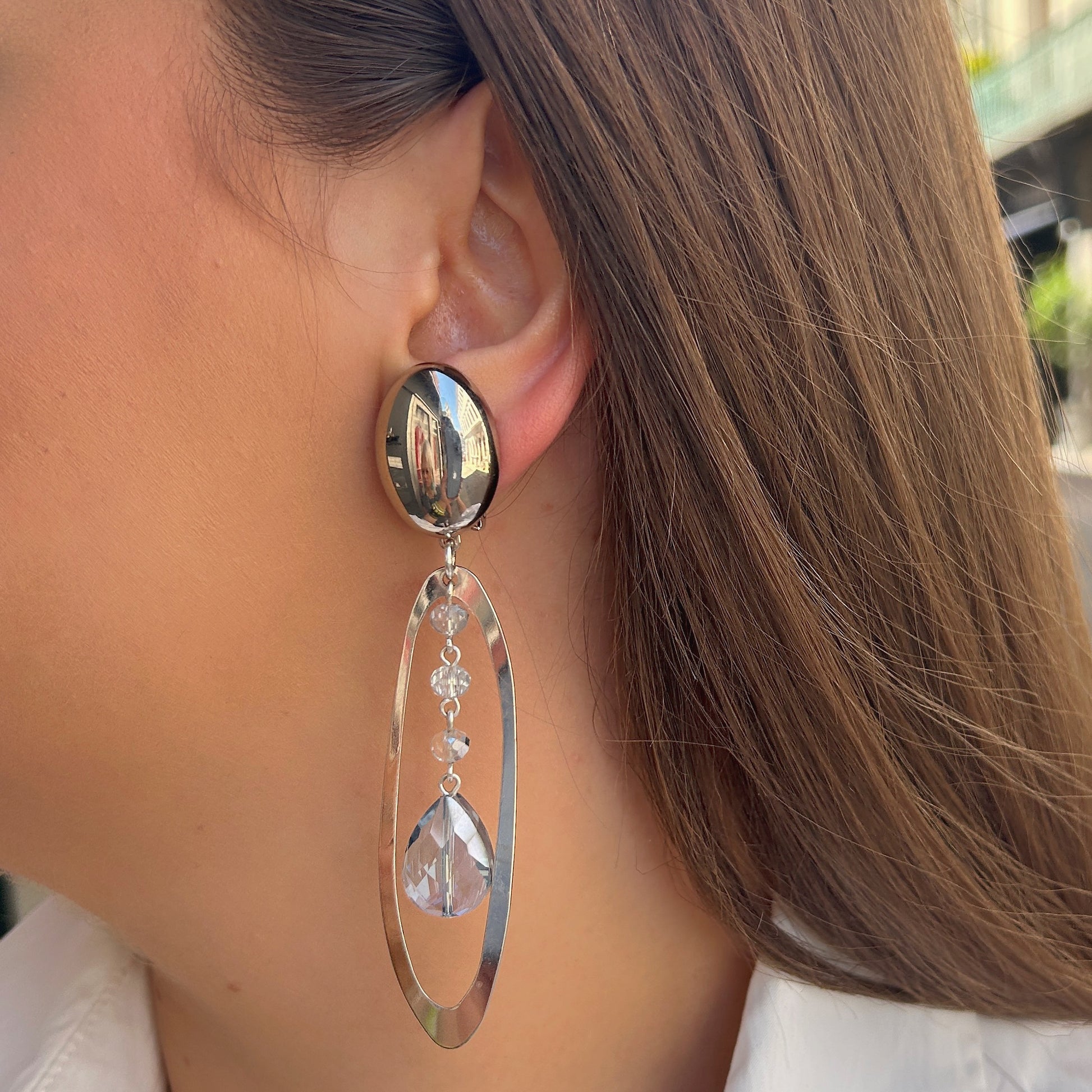 Boucles Cristol Silver Francine Bramli Paris en métal argenté avec cristaux facettés transparents et bleu glacier suspendus dans une monture ovale.