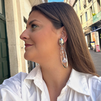 Boucles Cristol Silver Francine Bramli Paris en métal argenté avec cristaux facettés transparents et bleu glacier suspendus dans une monture ovale.