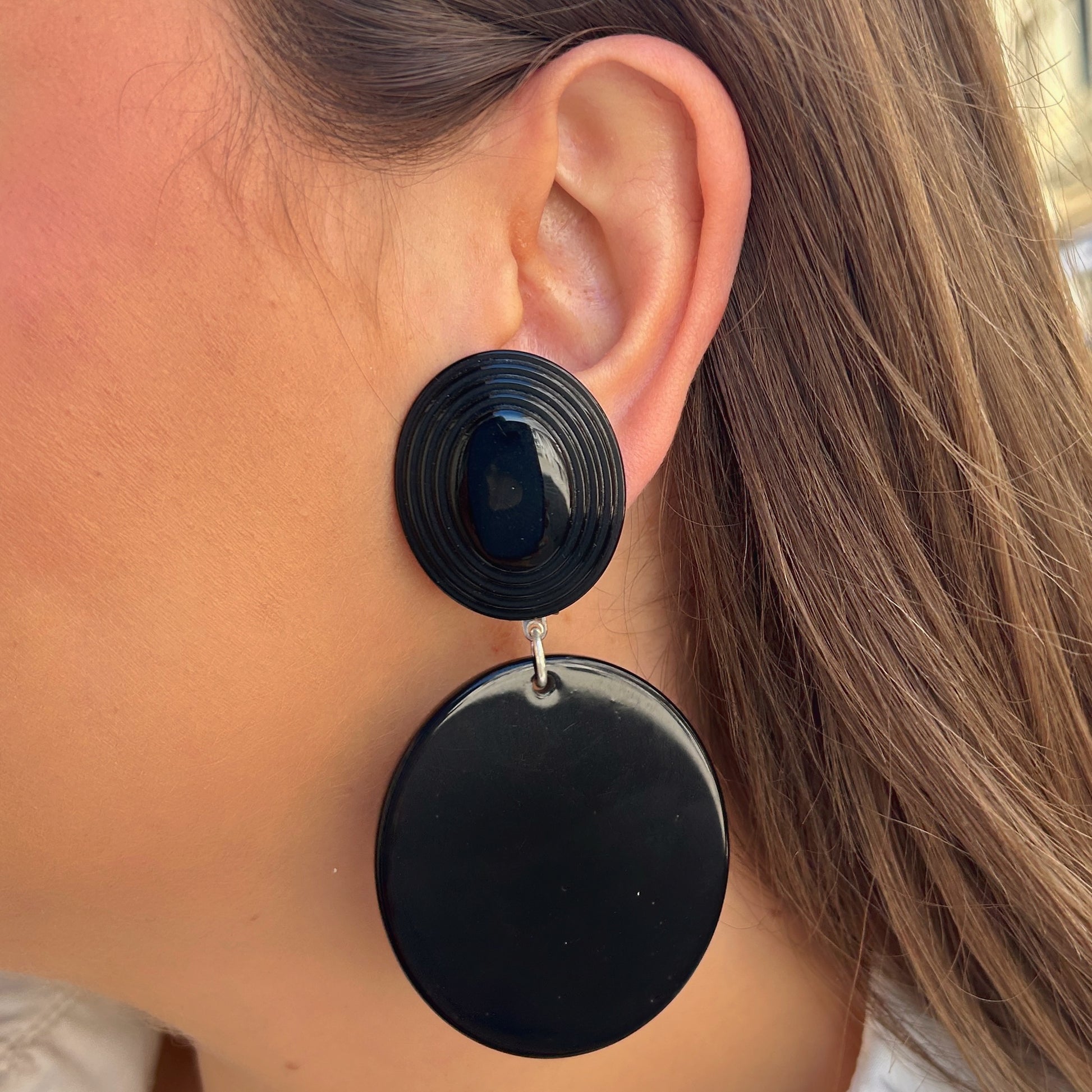 Boucles Hazel Noir Francine Bramli Paris avec cabochon ovale texturé noir et pendentif rond noir brillant portées sur mannequin chez Divinity Sète.