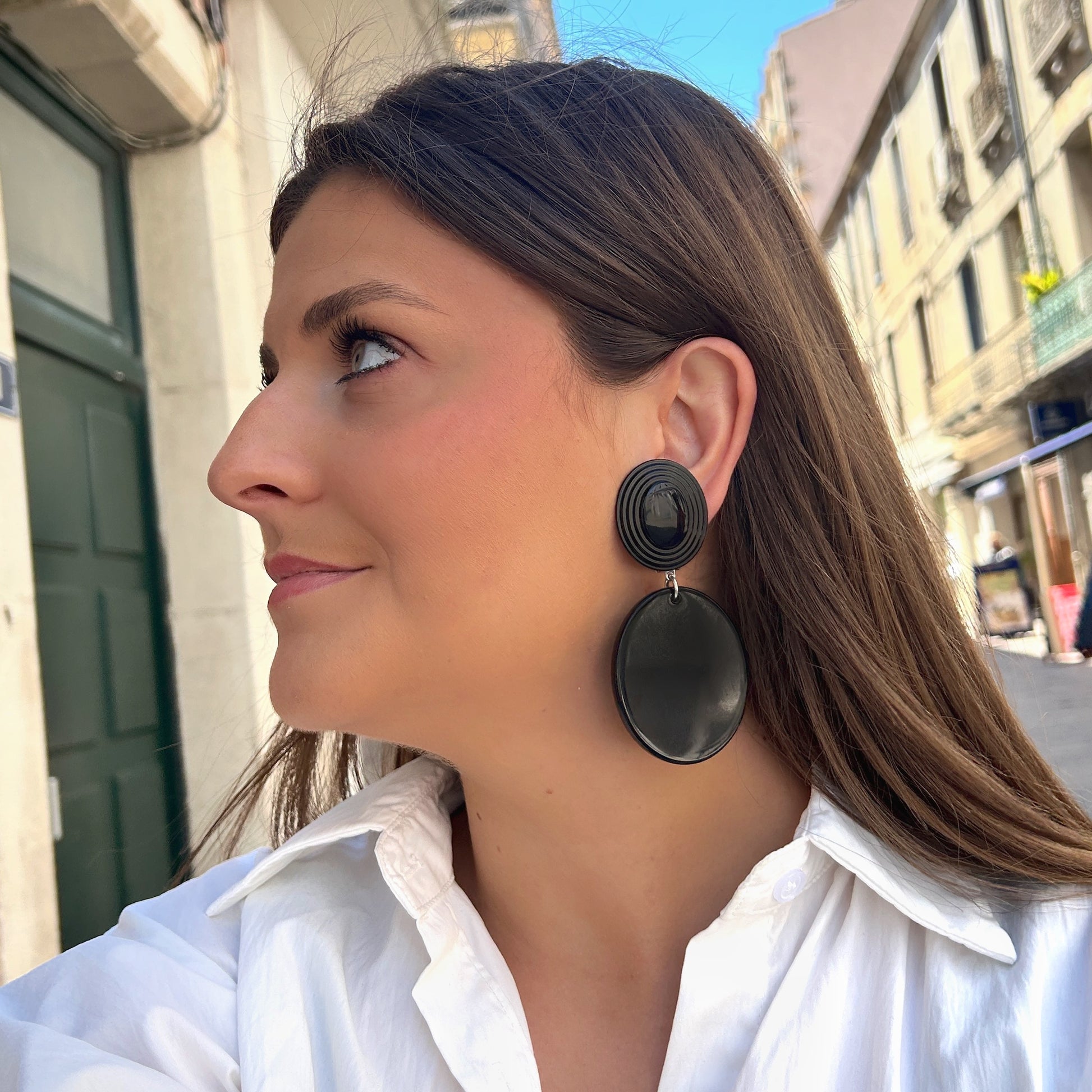 Boucles Hazel Noir Francine Bramli Paris avec cabochon ovale texturé noir et pendentif rond noir brillant portées sur mannequin chez Divinity Sète.