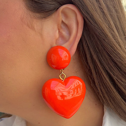 Boucles Heart Orange Francine Bramli Paris avec pendentif cœur oversize orange vif en résine brillante portées – boucles colorées tendance femme chez Divinity Sète
