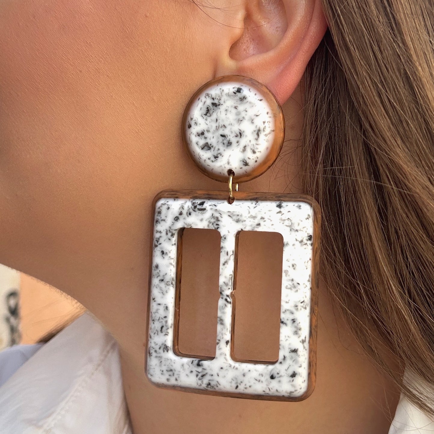 Boucles Lolita Simple Francine Bramli Paris en résine marbrée blanche et noire avec contour brun caramel et design géométrique ajouré.