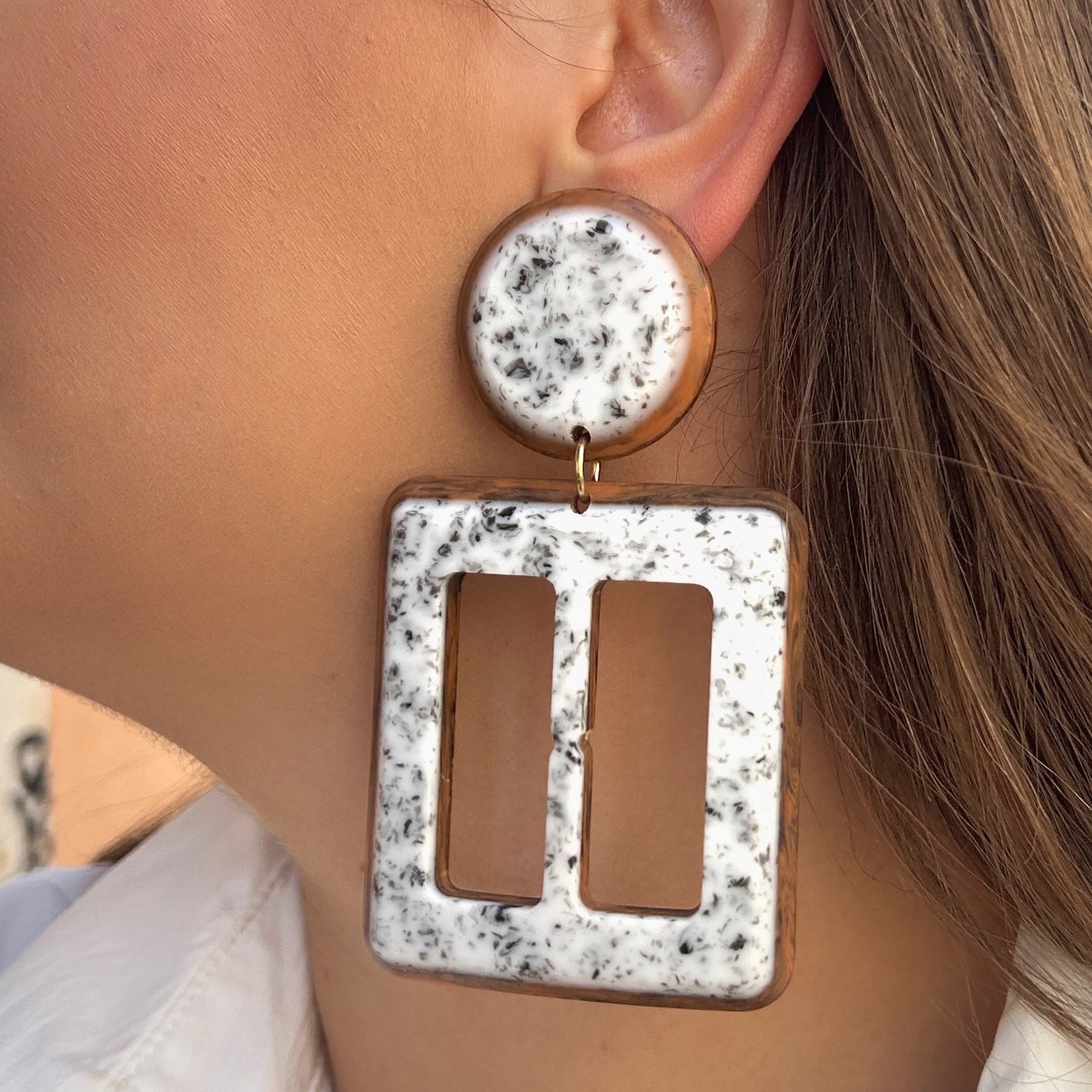 Boucles Lolita Simple Francine Bramli Paris en résine marbrée blanche et noire avec contour brun caramel et design géométrique ajouré.