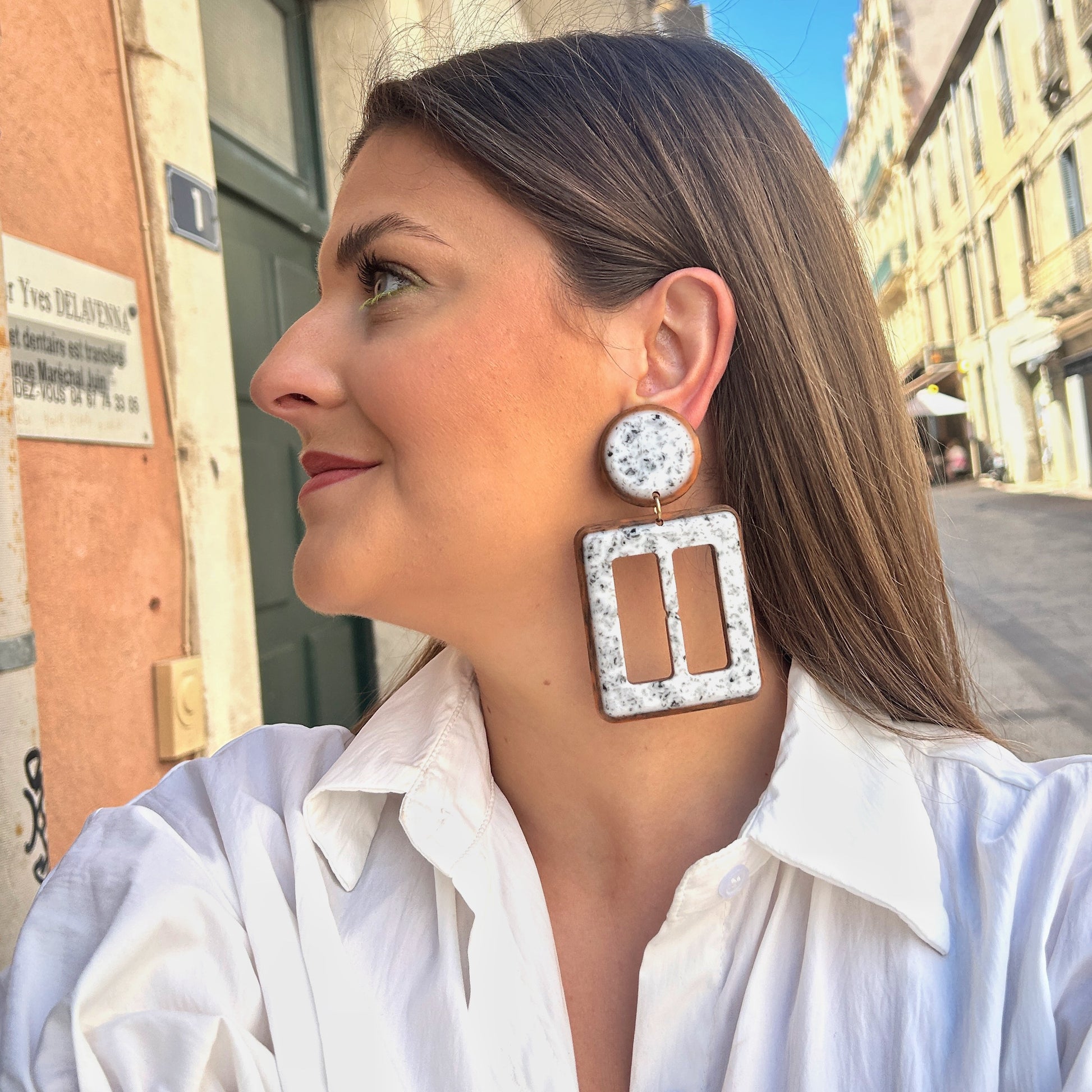 Boucles Lolita Simple Francine Bramli Paris en résine marbrée blanche et noire avec contour brun caramel et design géométrique ajouré.