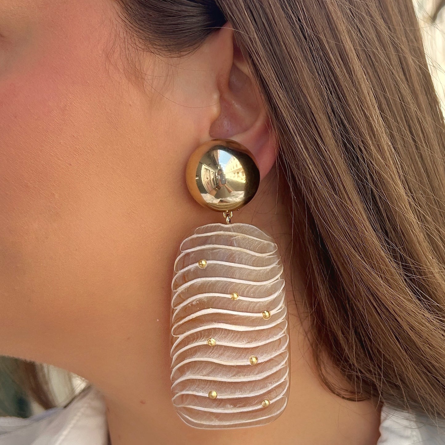 Boucles Ondara Francine Bramli Paris en résine nude texturée avec détails dorés et puce ronde miroir dorée, portées sur mannequin chez Divinity Sète.