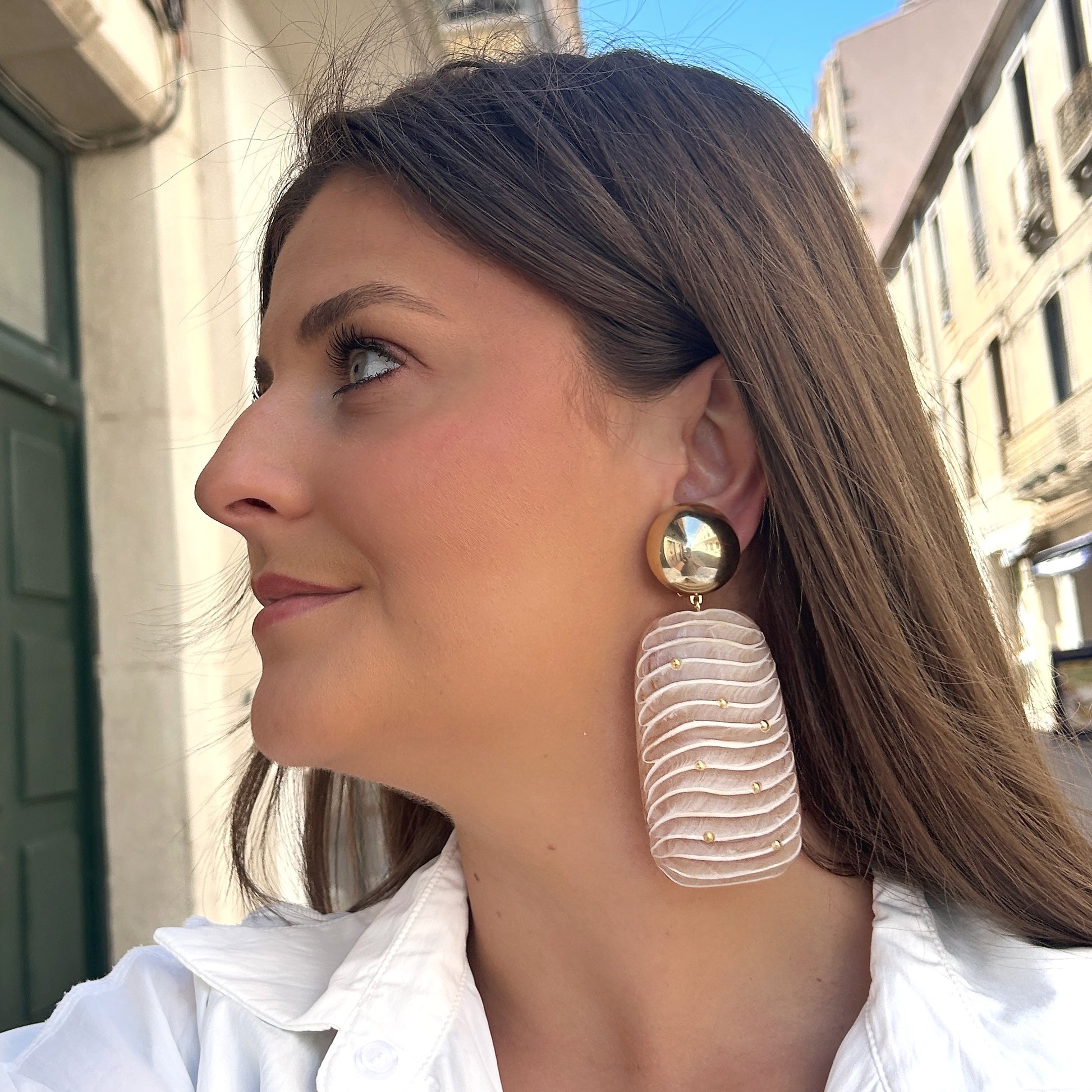 Boucles Ondara Francine Bramli Paris en résine nude texturée avec détails dorés et puce ronde miroir dorée, portées sur mannequin chez Divinity Sète.
