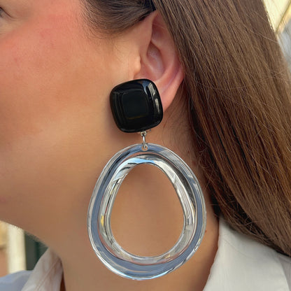 Boucles d’oreilles Abyssa Noir à clips Francine Bramli Paris, cabochons carrés noirs brillants et grands anneaux ovales transparents.