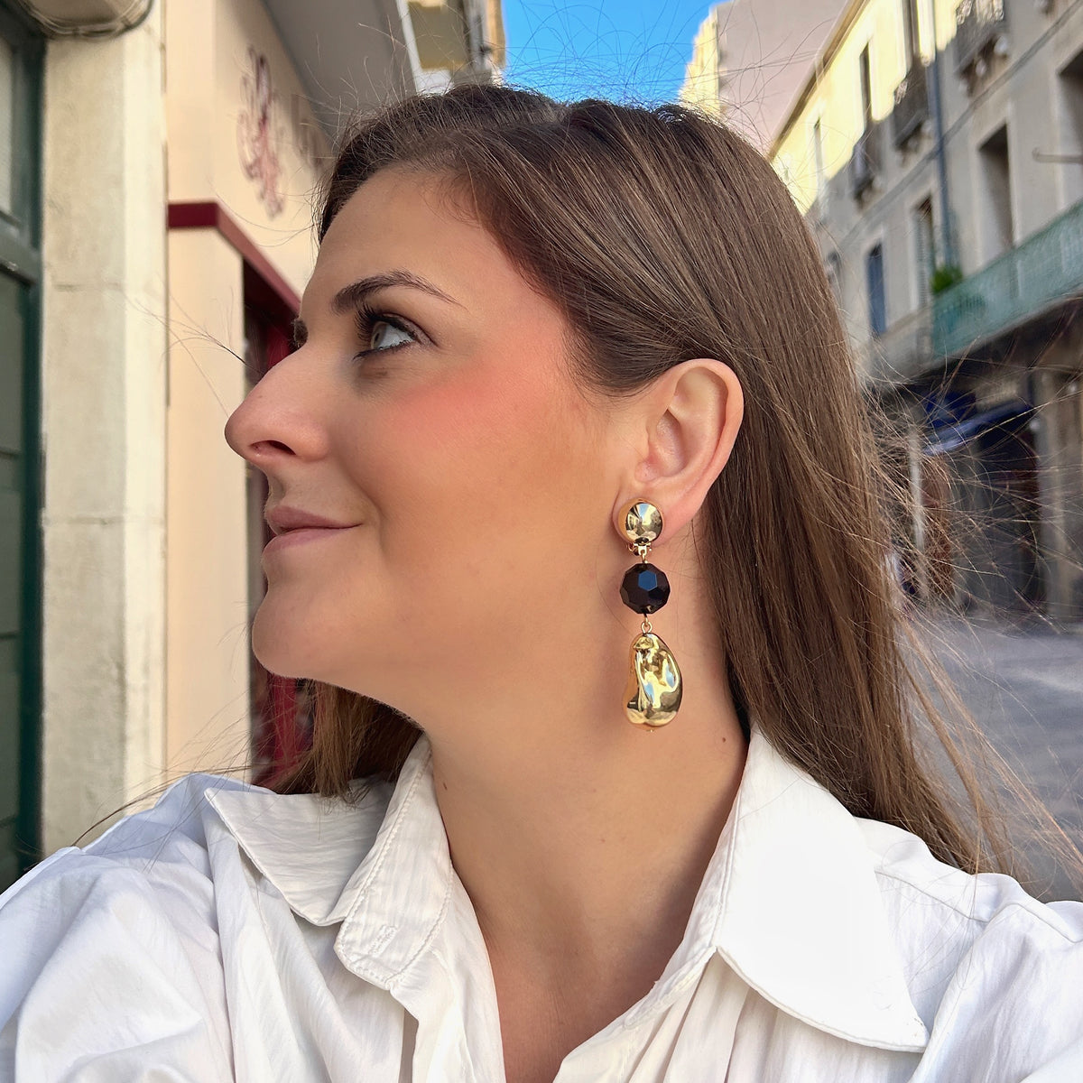 Boucles d'oreilles à clips Anastatia Noir Gold Francine Bramli Paris avec bouton rond doré effet miroir, perle noire facettée et pendentif goutte sculptural doré brillant – Divinity Sète.