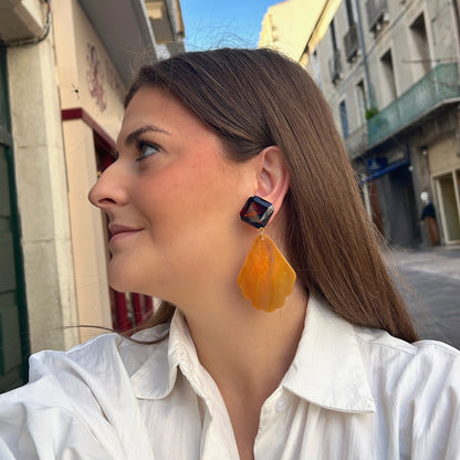 Boucles d’oreilles Aria à clips Francine Bramli Paris avec cabochons carrés facettés brun ambré et grands pendentifs orange marbré aux contours festonnés.