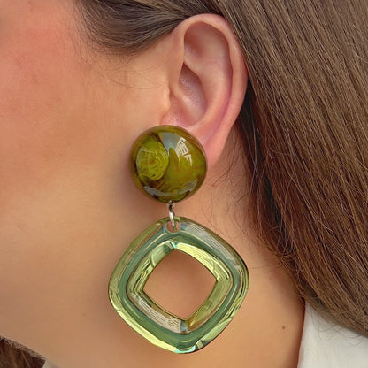 Boucles d’oreilles Asteria Vert à clips Francine Bramli Paris, cabochons ronds marbrés vert olive et grands pendentifs carrés ajourés translucides vert anis, chez Divinity Sète.